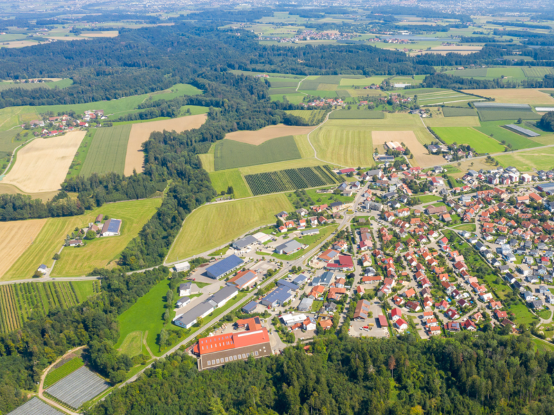 Luftaufnahme, die den gesamten Kernort Horgenzell erfasst, im Umland sind grüne Landschaften zu sehen.