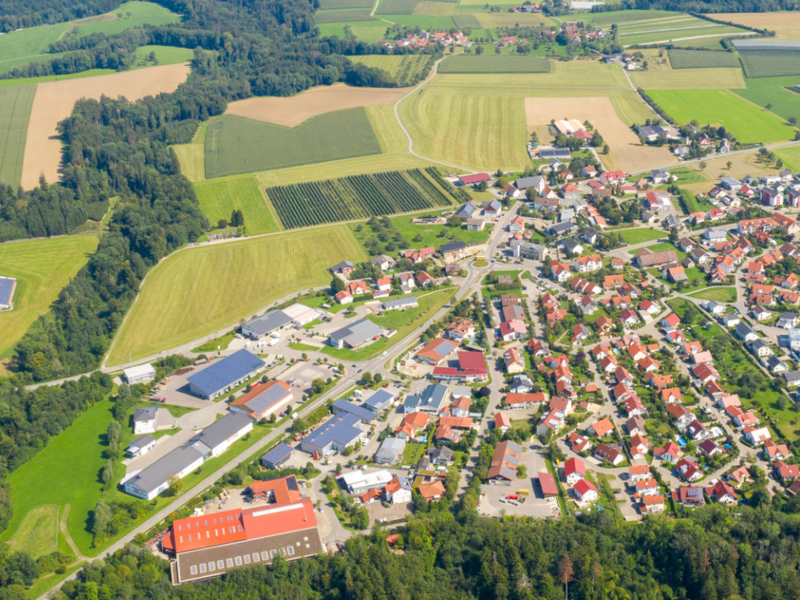 Luftaufnahme, die den gesamten Kernort Horgenzell erfasst, im Umland sind grüne Landschaften zu sehen.