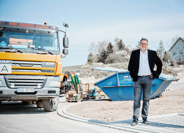 Bürgermeister Volker Restle steht neben einem Baustellenfahrzeug und vor einem Bauschuttcontainer. Aufnahmeort ist in einem Baugebiet, dass gerade erschlossen wird