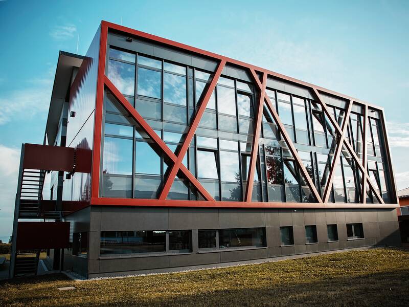 Neubau der Gemeinschaftsschule Horgenzell in melancholischer Stimmung, davor ist ein Grünstreifen zu sehen, im Hintergrund blauer Himmel mit leichten Wolken